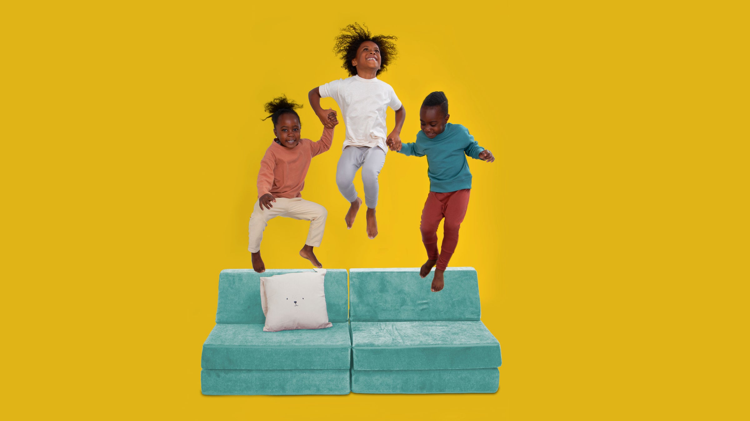 three kids jumping and laughing on a play sofa