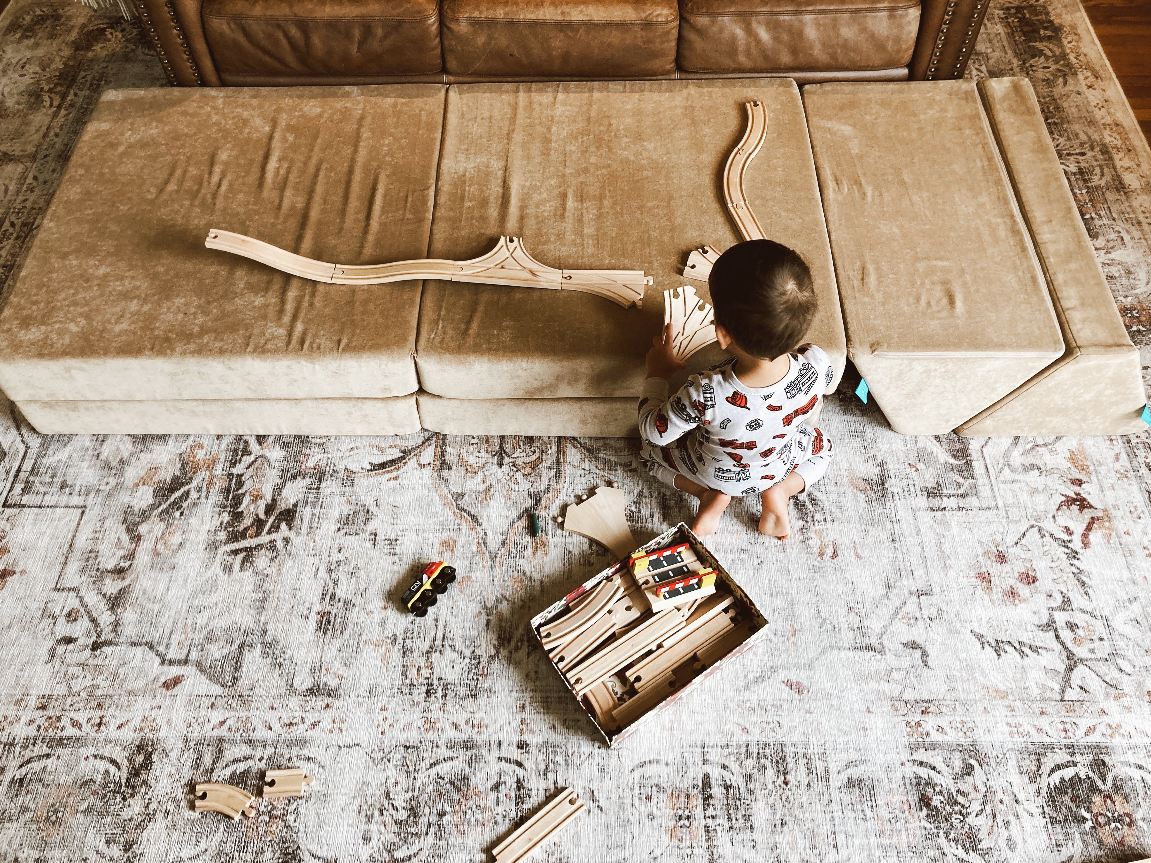 boy using the coconut play couch as a table to play with trains