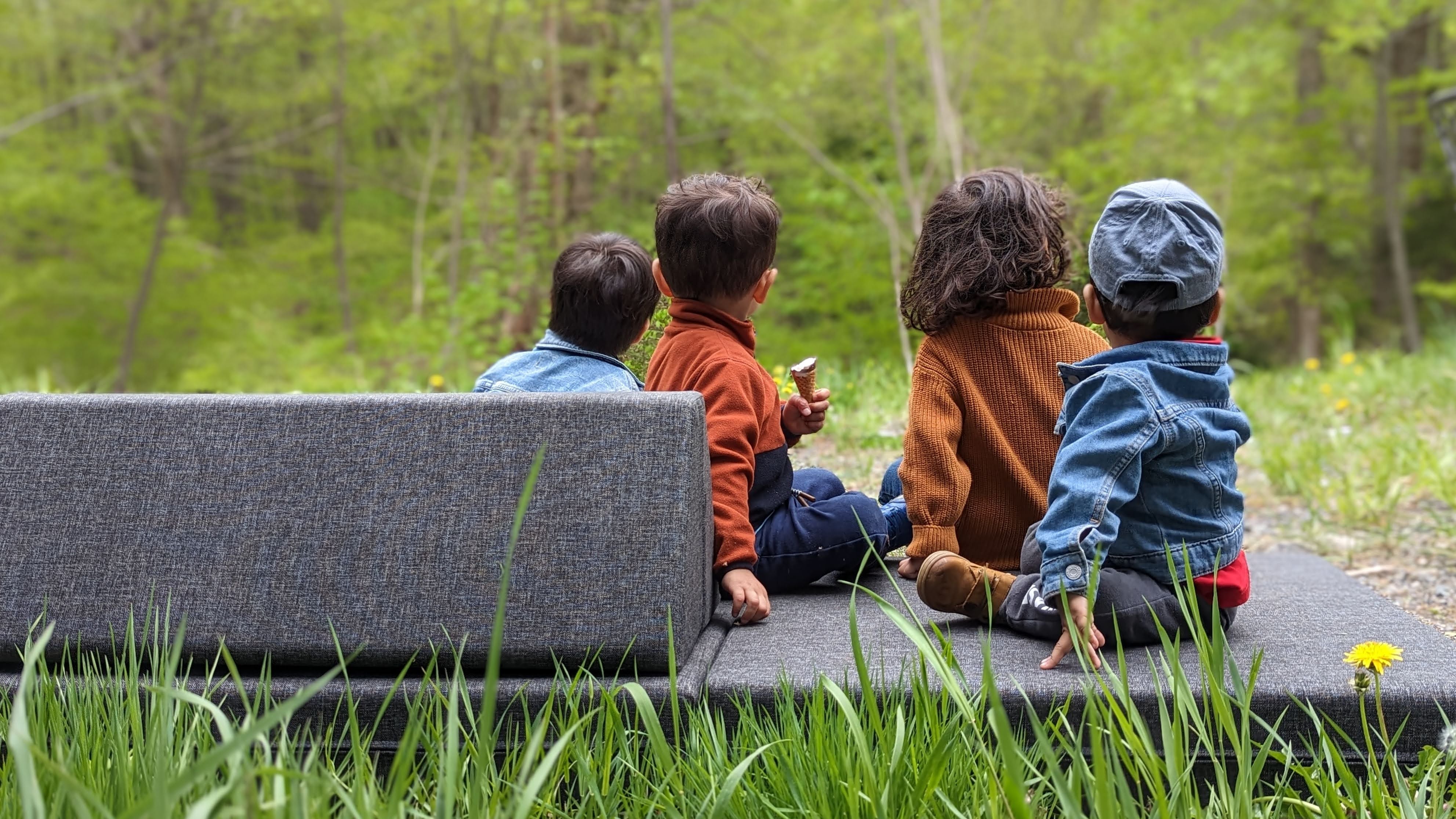 kids sitting on an adventure play couch outdoors looking at the horizon